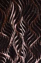 Textured seamless abstract background with wiggle pattern creating wavy ornament on dark thick fabric with creative design and glossy surface