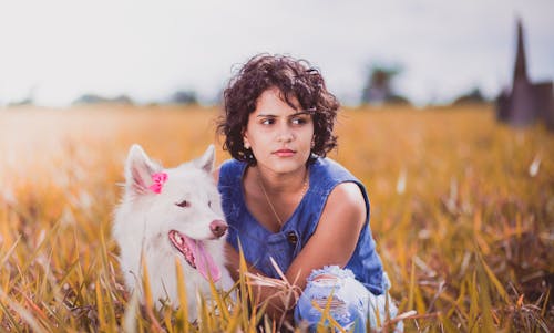 Mulher Agachada Perto De Cachorro Branco No Campo De Grama