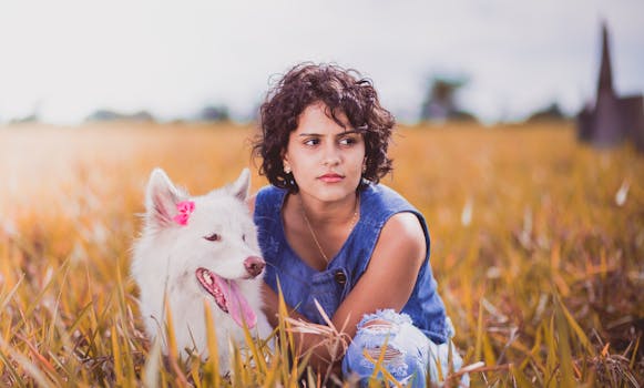 一名妇女和她的白狗在阳光明媚的田野里放松身心，享受自然的陪伴
