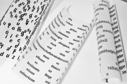 From above of rolled sheets of paper with inscriptions written in German language placed on white background in light room