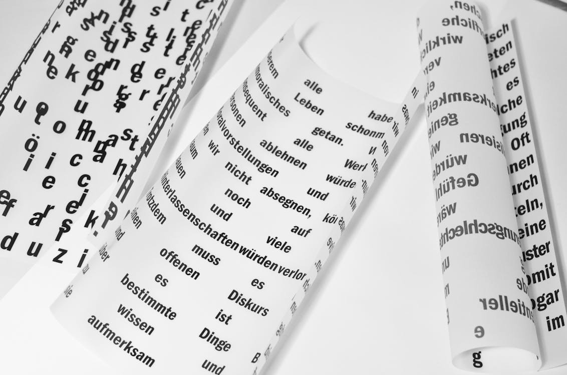 From above of rolled sheets of paper with inscriptions written in German language placed on white background in light room