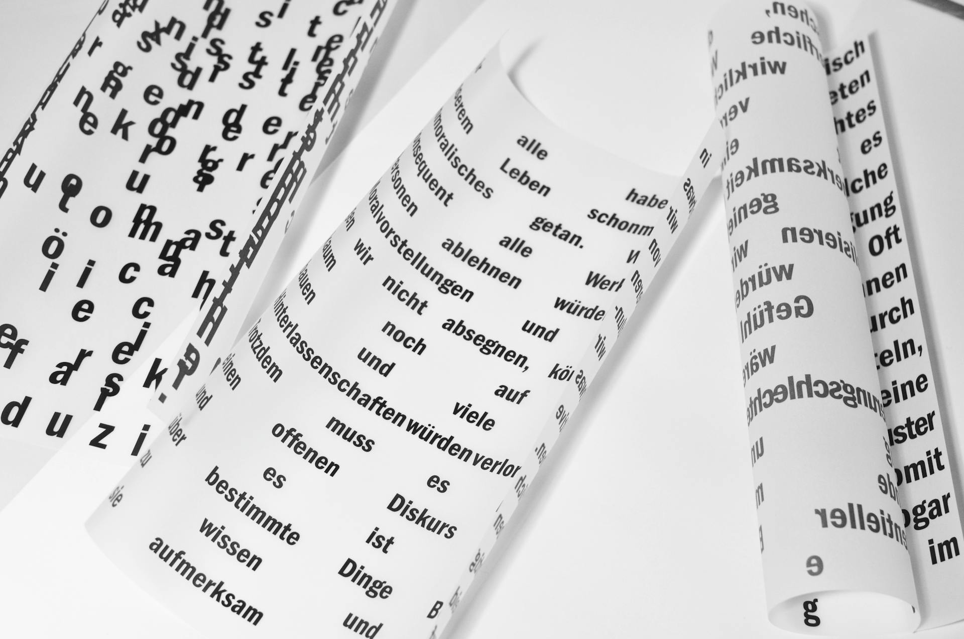 From above of rolled sheets of paper with inscriptions written in German language placed on white background in light room