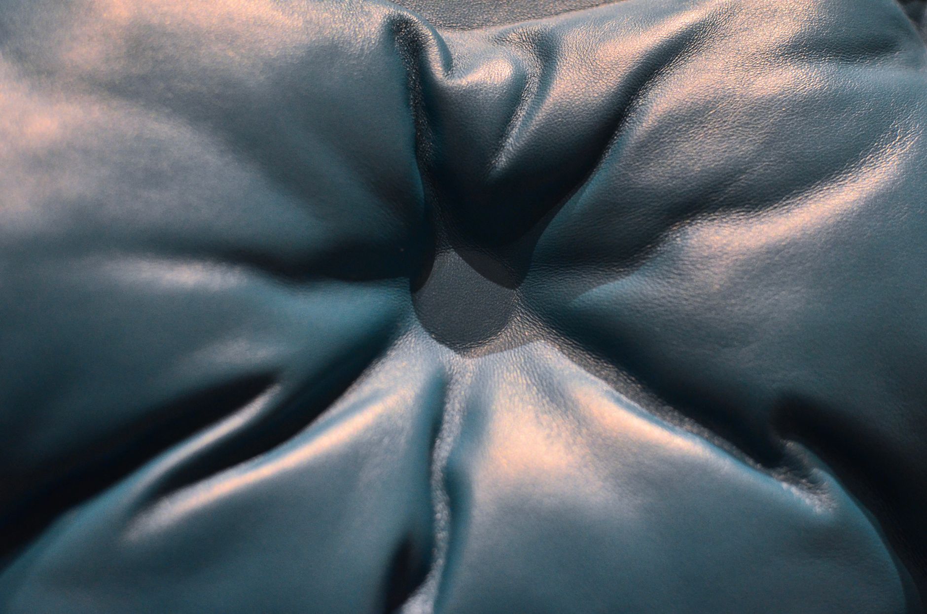 Closeup of black leather couch with carriage coupler and button with light glares placed in light room in cozy flat