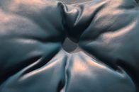 Closeup of black leather couch with carriage coupler and button with light glares placed in light room in cozy flat