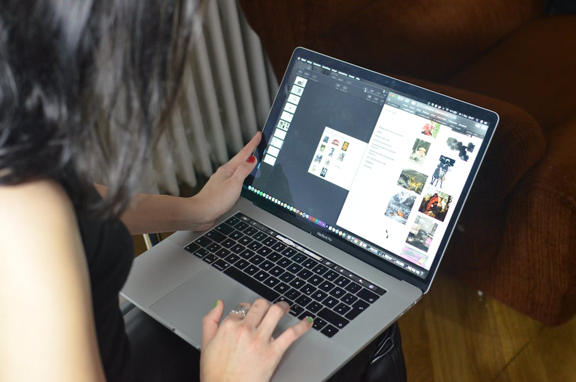 Vista lateral de uma mulher irreconhecível com cabelo escuro, olhando para a tela e navegando em um netbook contemporâneo enquanto trabalhava online em casa