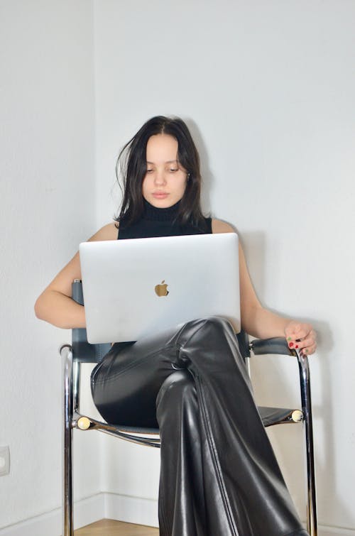 Kobieta W Czarnej Sukni Siedzi Na Krześle Przy Użyciu Macbooka