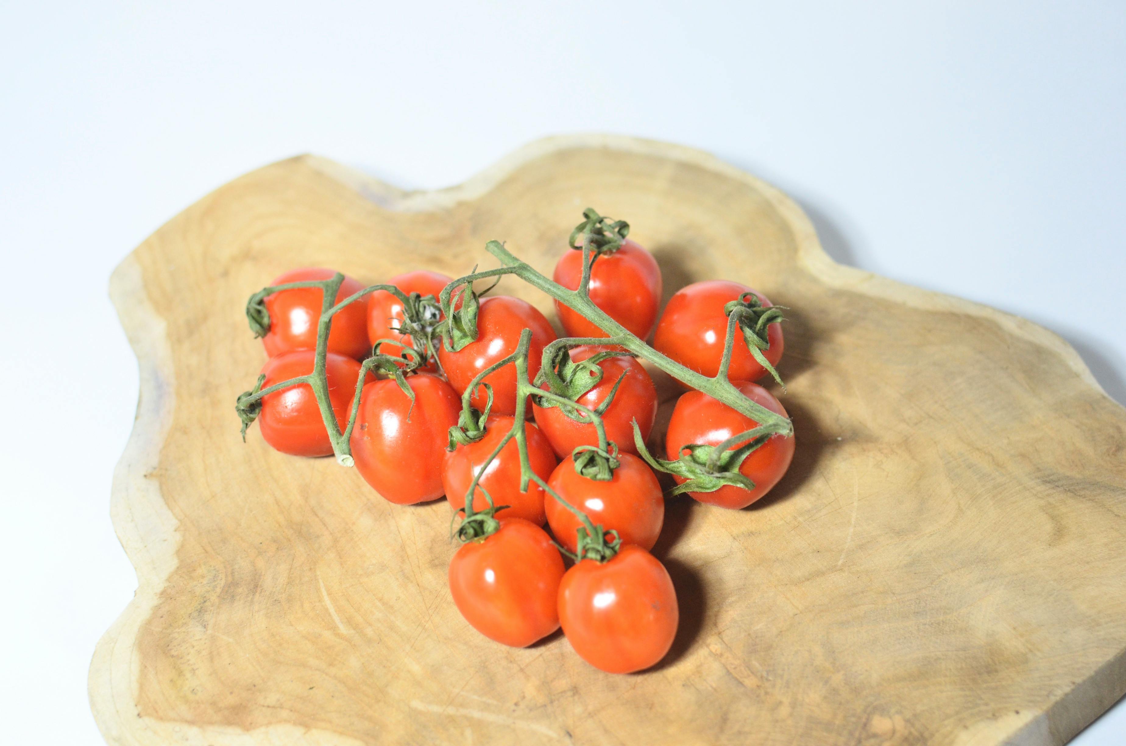 tomatoes on branch placed on wooden board