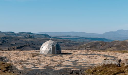 Free A geodesic dome tent set in the rugged Icelandic landscape with clear blue skies. Stock Photo