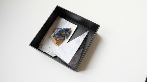 From above of colorful stone azurite placed in black box on white table in light room