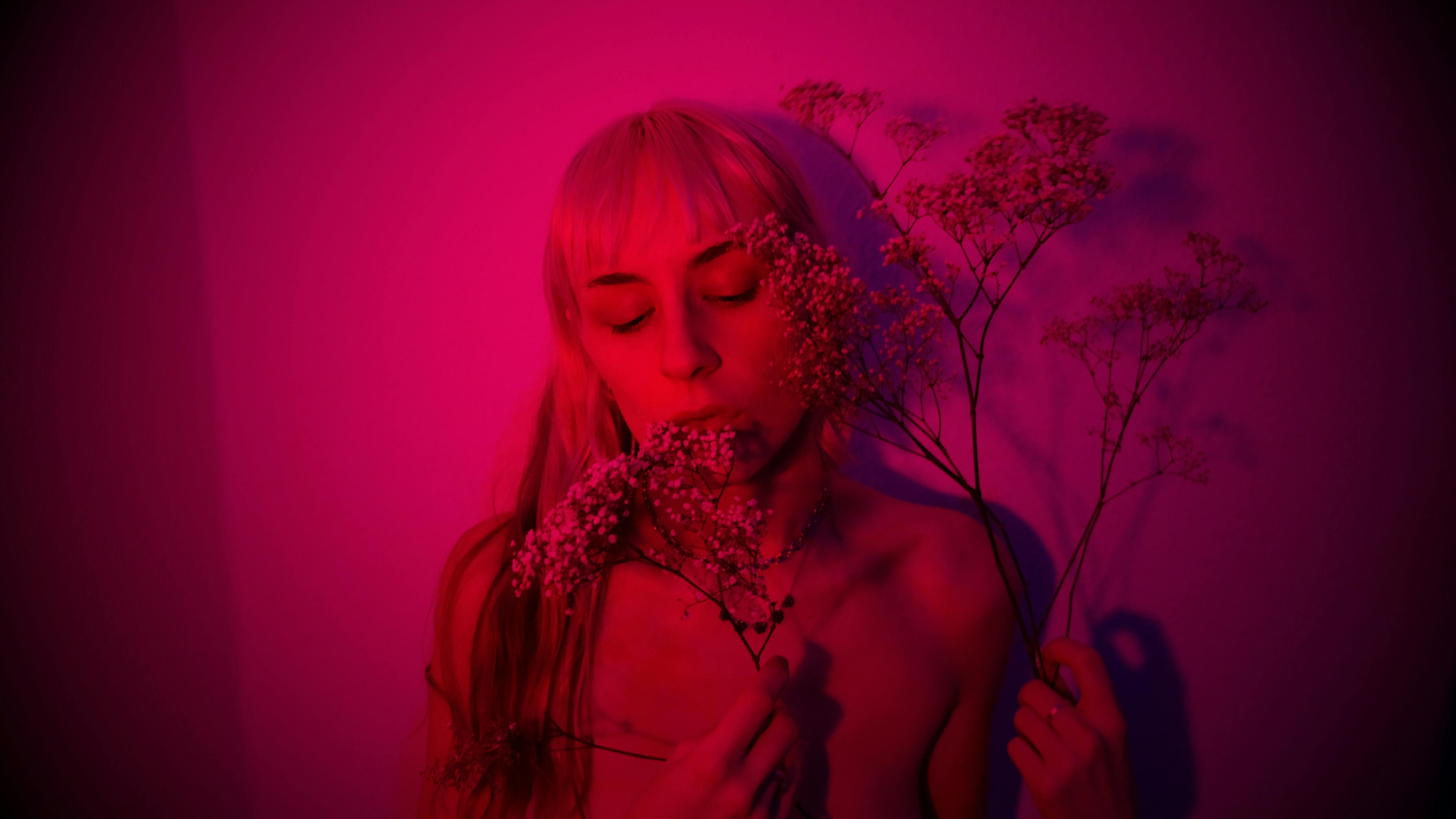 naked woman with plant in purple neon light