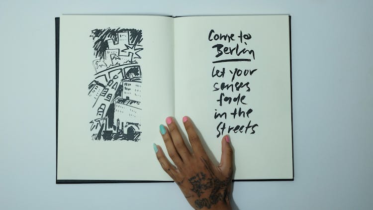 Unrecognizable Woman With Opened Sketchbook With Inscription And Drawing