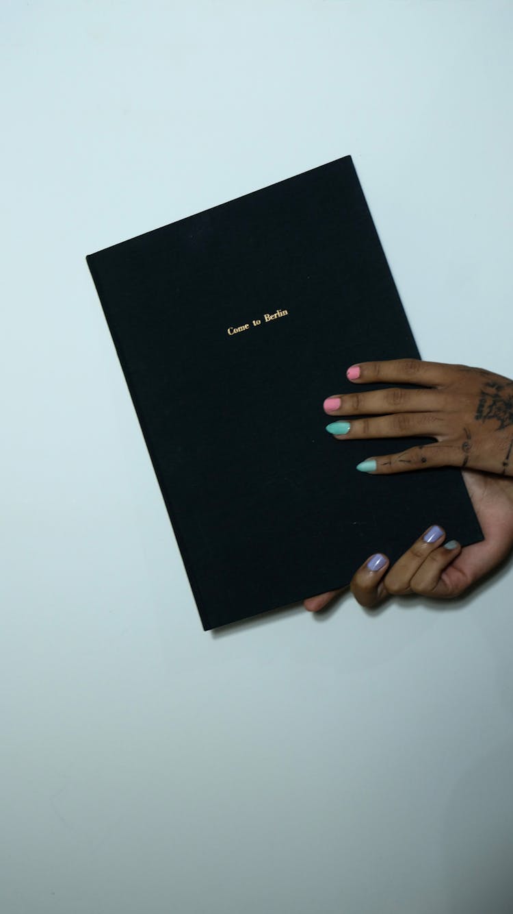 Crop Woman Showing Book With Black Hardcover