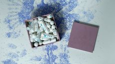A pink box filled with tampons on a creative speckled blue and white surface.