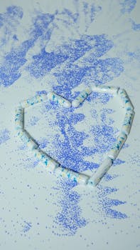 Creative heart-shaped arrangement of tampons against a speckled blue background, symbolizing feminine care.