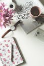 这是一张别致的女性工作空间俯视图，画面中摆放着咖啡、鲜花和文具