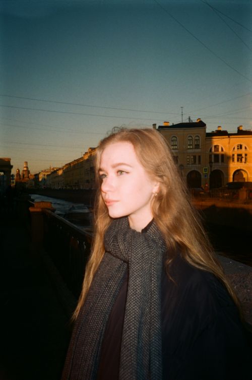 Free A serene portrait of a woman by a canal in Saint Petersburg during golden hour. Stock Photo