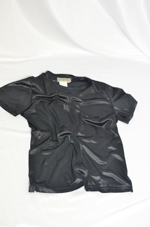 Black shiny t shirt with short sleeves against white background