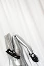 Inflatable silver mannequin with folded legs and black shoes with clasp placed on white fabric