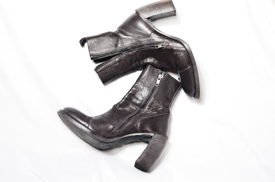 Top view of pair of dark brown leather boots with zipper and wide high heels placed on white background