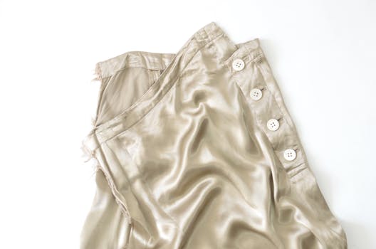 Close-up of a beige silk skirt with buttons on a white background. Perfect for fashion design concepts.