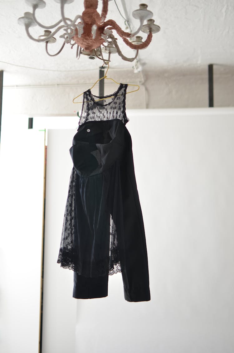 Black Trousers And Transparent Dress On Hanger Placed On Chandelier