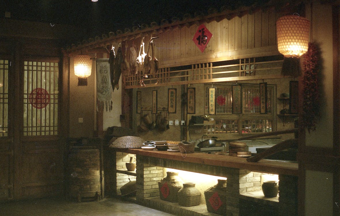 Interior of oriental restaurant with wooden door near counter and dim illumination from lamps