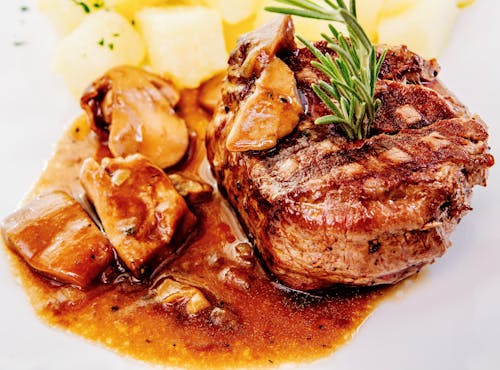 Foto de archivo de carne cocida con verduras verdes en un plato de cerámica blanca