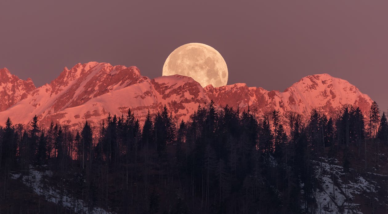 Moon Rising Behind the Snow Capped Mountain