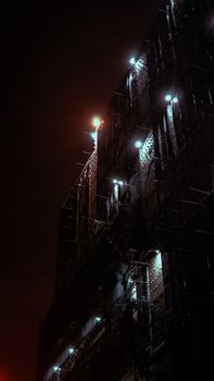 Mysterious construction site illuminated by spotlights at night, creating a dramatic urban scene.