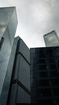 Low angle view of modern skyscrapers against a cloudy sky, showcasing architectural design.