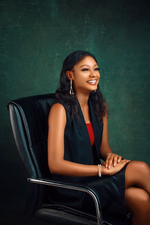 Free Portrait of a smiling woman seated in an elegant indoor setting. Perfect for lifestyle and fashion themes. Stock Photo