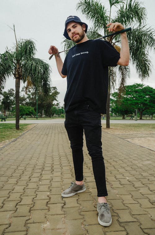 Man in Black Crew Neck T-shirt and Black Pants Standing on Gray Concrete Pavement