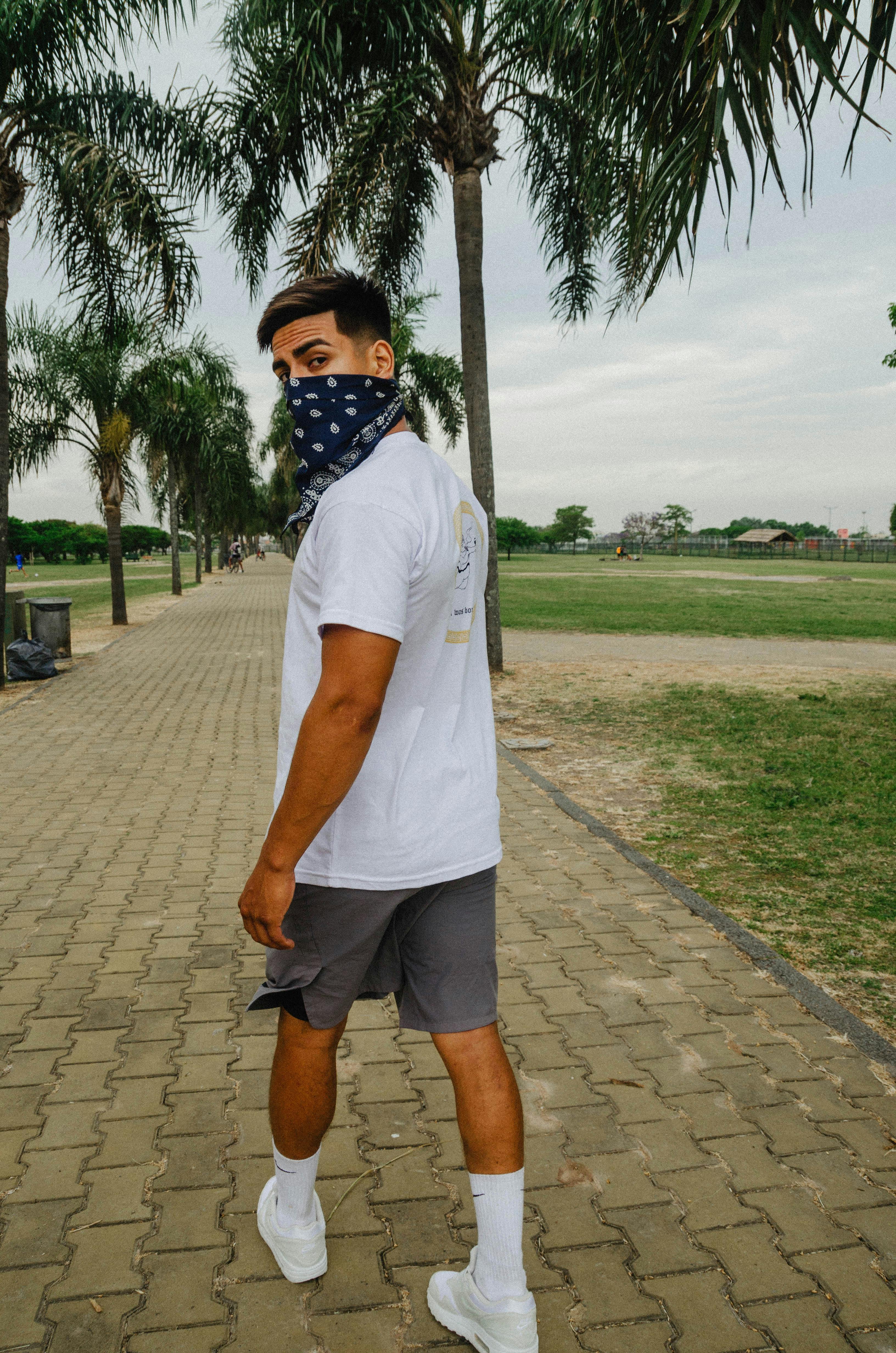 man with bandana covering mouth walking in a pathway