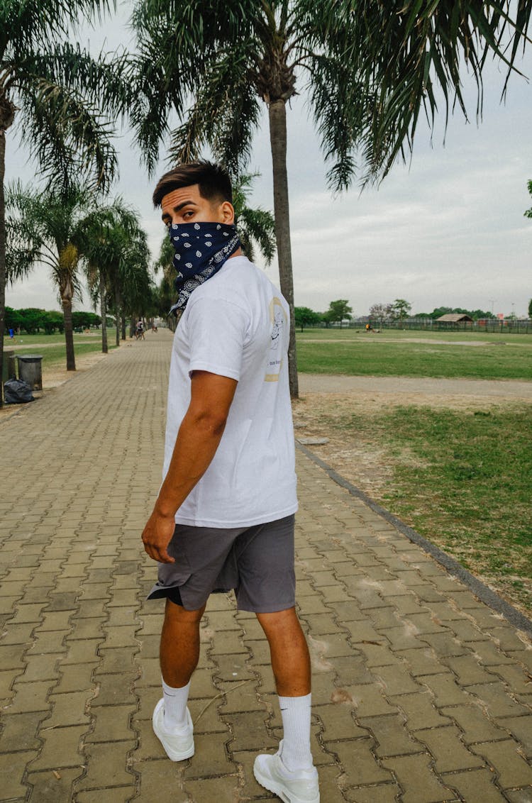 Man With Bandana Covering Mouth Walking In A Pathway