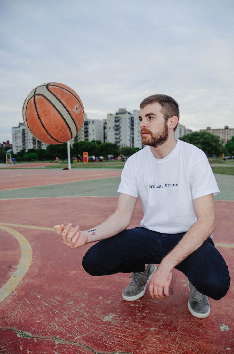 Man Squatting And Tossing Basketball