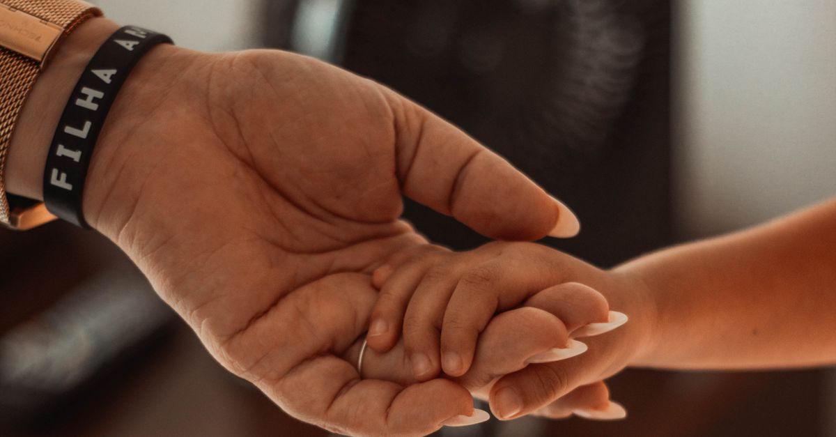 Emotional close-up of a parent and child holding hands, showing connection and love.
