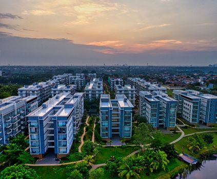 Living district with typical buildings on green shore of river under cloudy sunset sky