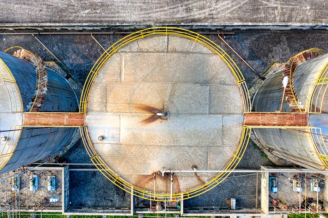 Top view of huge industrial tanks connected with rusty passages located at territory of factory
