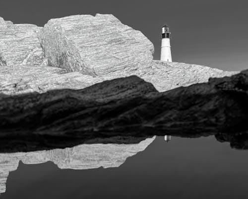 Lighthouse on stony shore of reflective sea
