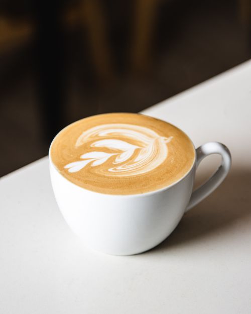 Free Beautiful latte art in a white cup on a cafe table, showcasing intricate foam designs. Stock Photo