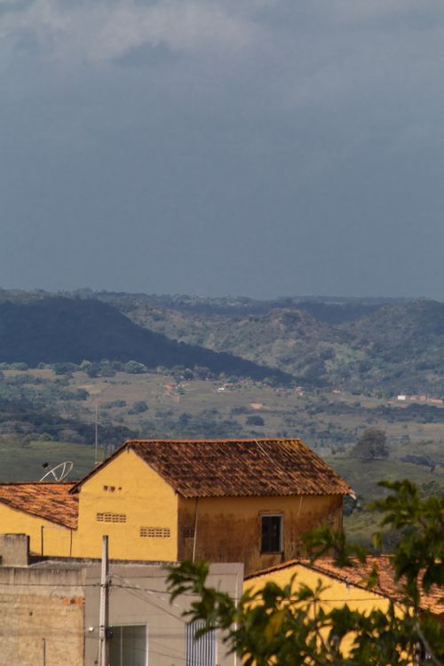 Free A beautiful view of rural rooftops against a backdrop of rolling hills in a countryside setting. Stock Photo