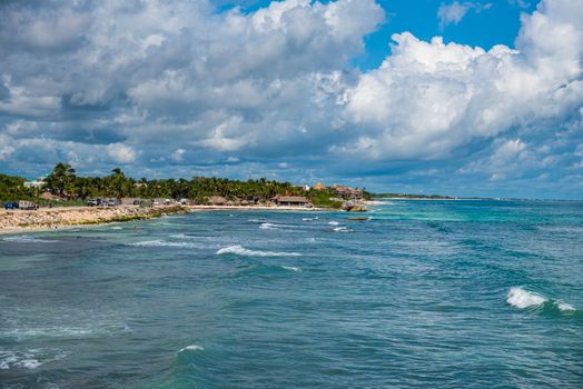 Vibrant coastal view of Tulum with turquoise waters and lush greenery under bright blue skies.