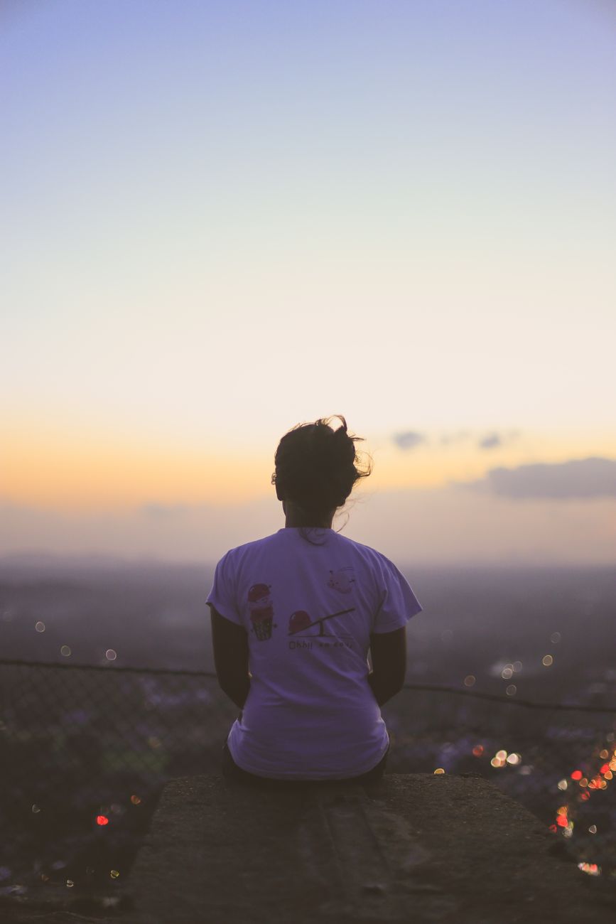 Back view of a person watching a serene sunset from a hilltop in Kurunegala, Sri Lanka.