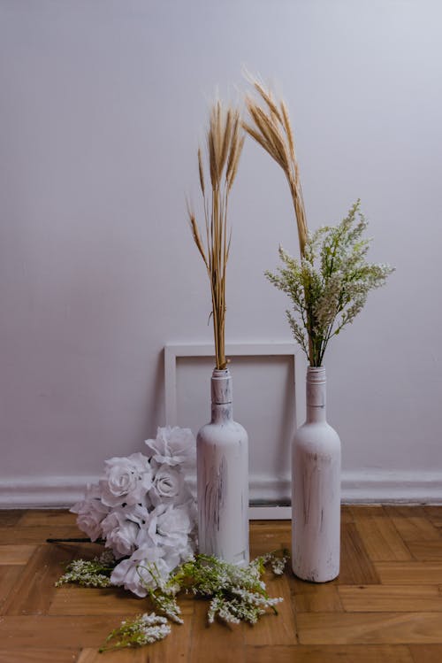 Artificial Flowers and Painted Bottles on Wooden Floor