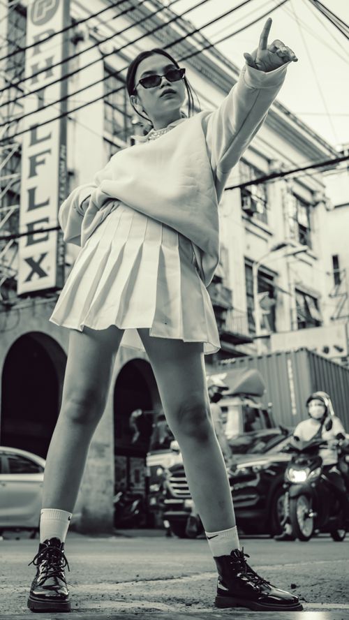 Free Asian woman posing stylishly on street with cityscape backdrop in Manila. Stock Photo