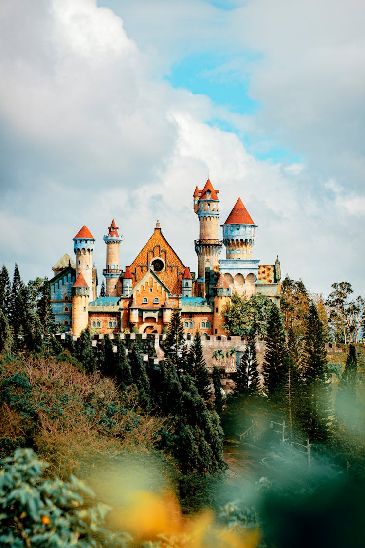 Castle Exterior In Theme Park Under Fluffy Clouds