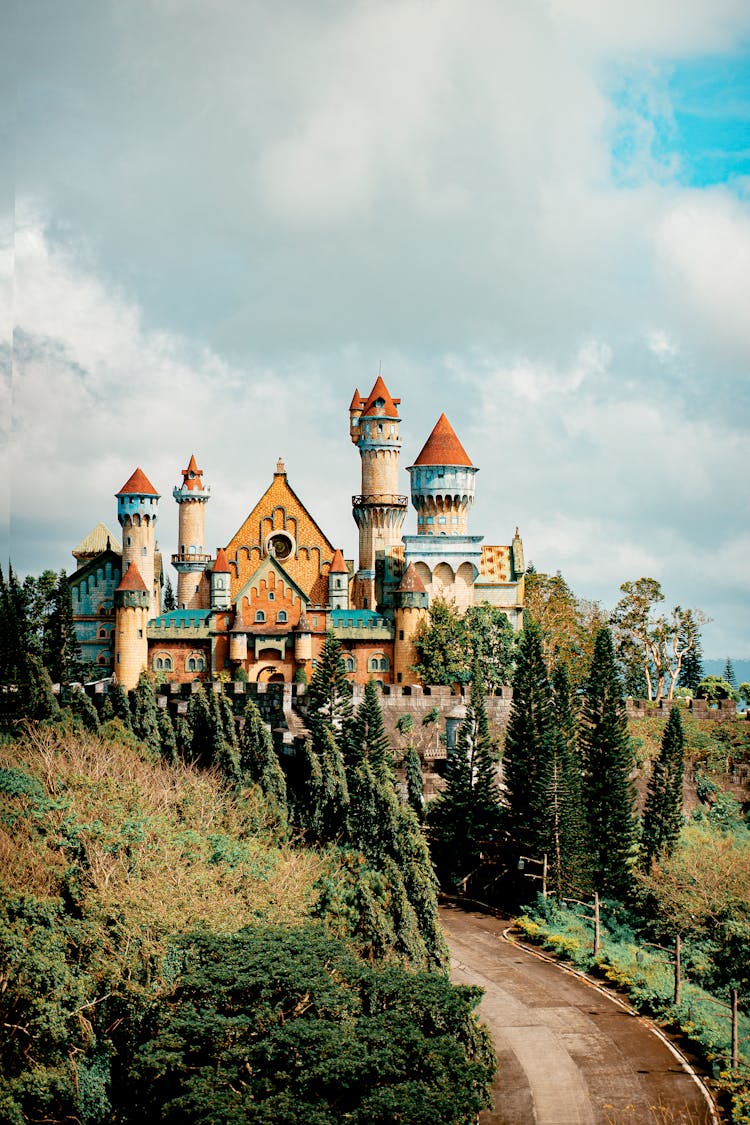 Road Against Castle Facade In Theme Park Under Cloudy Sky