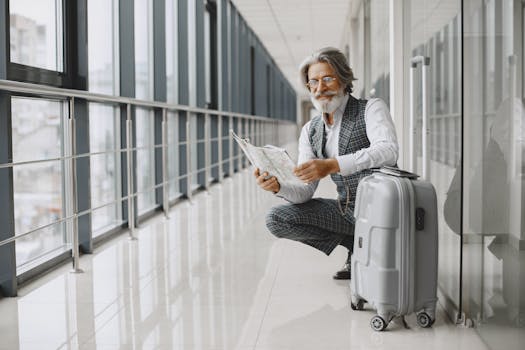 Senior man in airport hallway holding a map, sitting beside luggage, illustrating travel and exploration.
