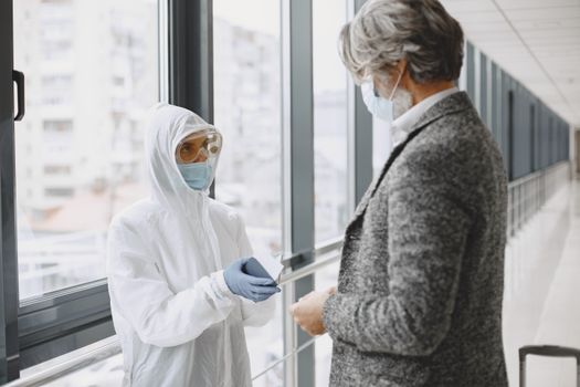 Two healthcare professionals in protective gear discussing in a hospital hallway.