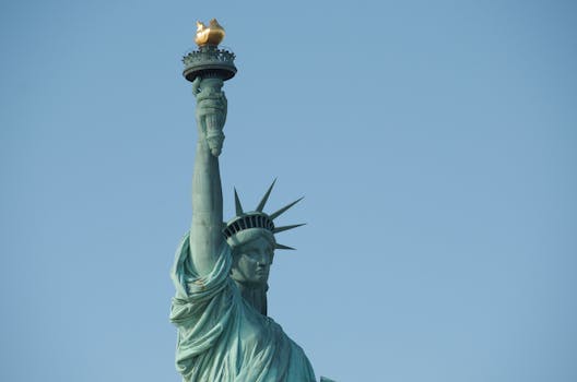 Close-up view of the Statue of Liberty's torch and crown against a clear blue sky.